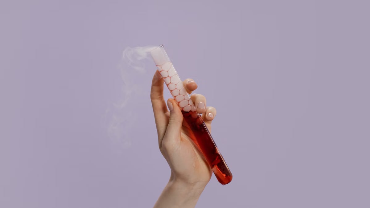 A hand holds a smoking test tube with vibrant red liquid and vapor, symbolizing scientific experimentation.